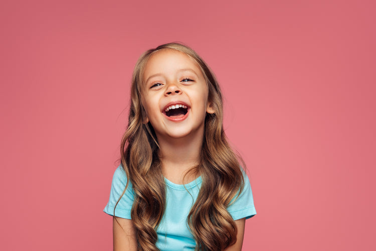 Young girl smiling wide with clean teeth, showing kids dental and oral care.