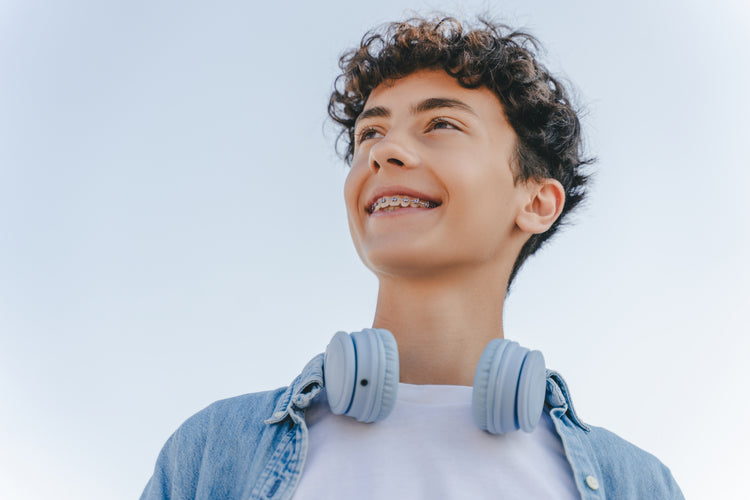 Teen smiling with braces, showing healthy teeth and dental care.