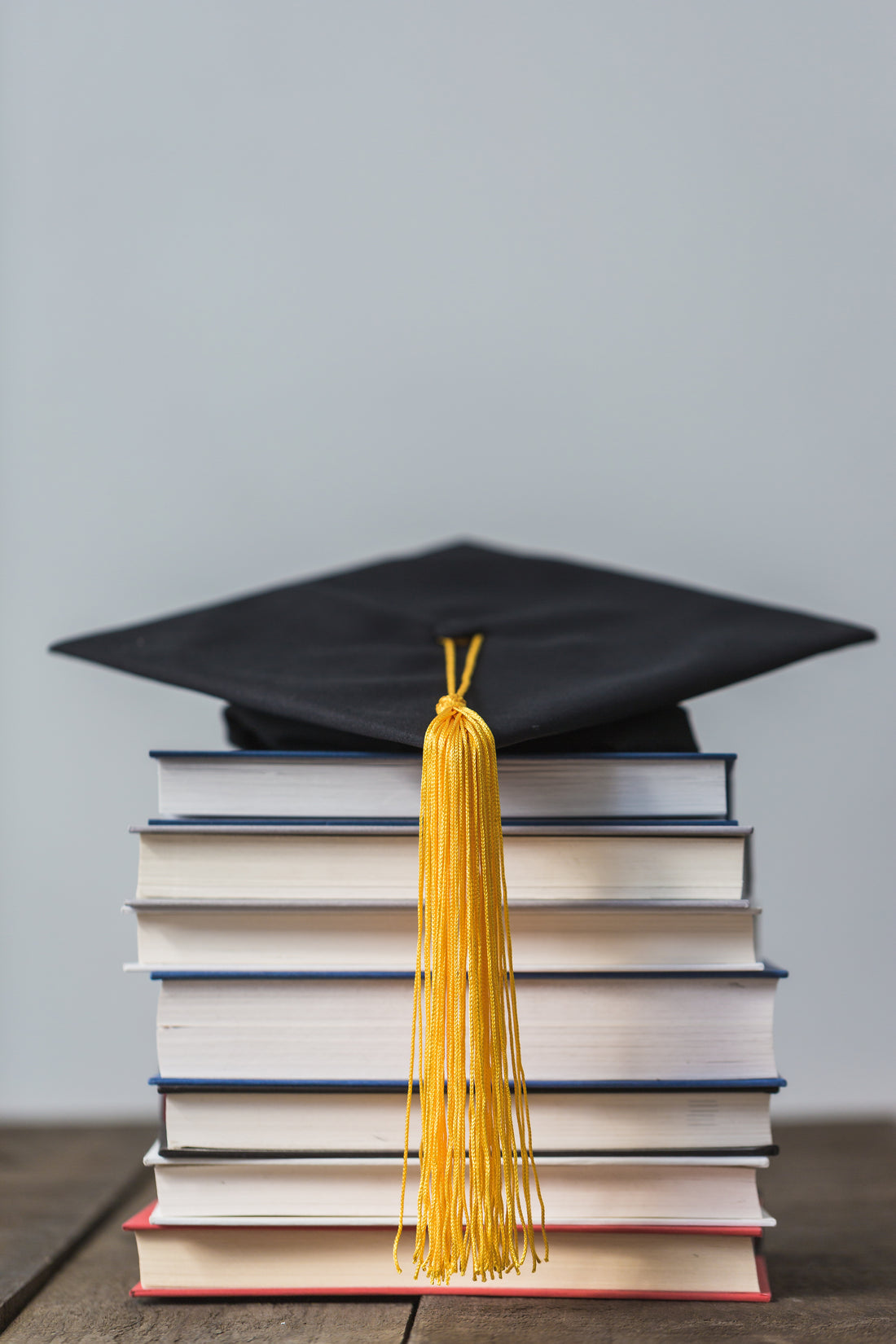 Graduation cap with gold tassel on stacked books, symbolizing dental education and oral care training.